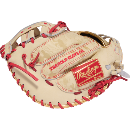 The Rawlings Heart of the Hide 33" Kinzie Hansen K9 Fastpitch Catcher's Mitt (PROCM33FP-24CS) features tan and red leather, red laces, gold accents, and THE GOLD GLOVE CO. and Rawlings logos, inspired by a classic catcher’s mitt design.