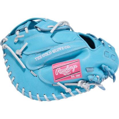 The Rawlings Heart of the Hide 34" Fastpitch Catcher's Mitt (PROCM34FP-24CBW) is light blue with white laces, a pink “Rawlings” and “Est. 1887” patch, plus “THE GOLD GLOVE CO.” embroidered in white.