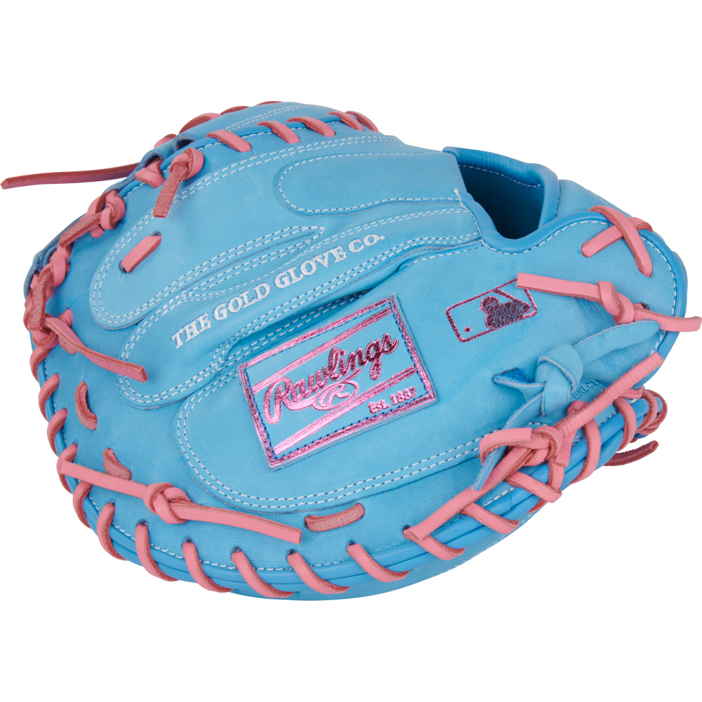 The Rawlings Heart of the Hide 33" catcher's mitt (PRORCM33-23CBP) is light blue with pink laces, stitching, and a pink Rawlings logo patch. It features "THE GOLD GLOVE CO." stamped on the outer side.