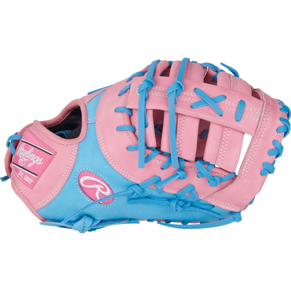 The Rawlings Heart of the Hide 12.25" First Base Mitt (PRORDCTU-10PCB) features a pink and light blue design with blue laces, pink patches, ContoUR Fit, and bold Rawlings branding on the thumb.