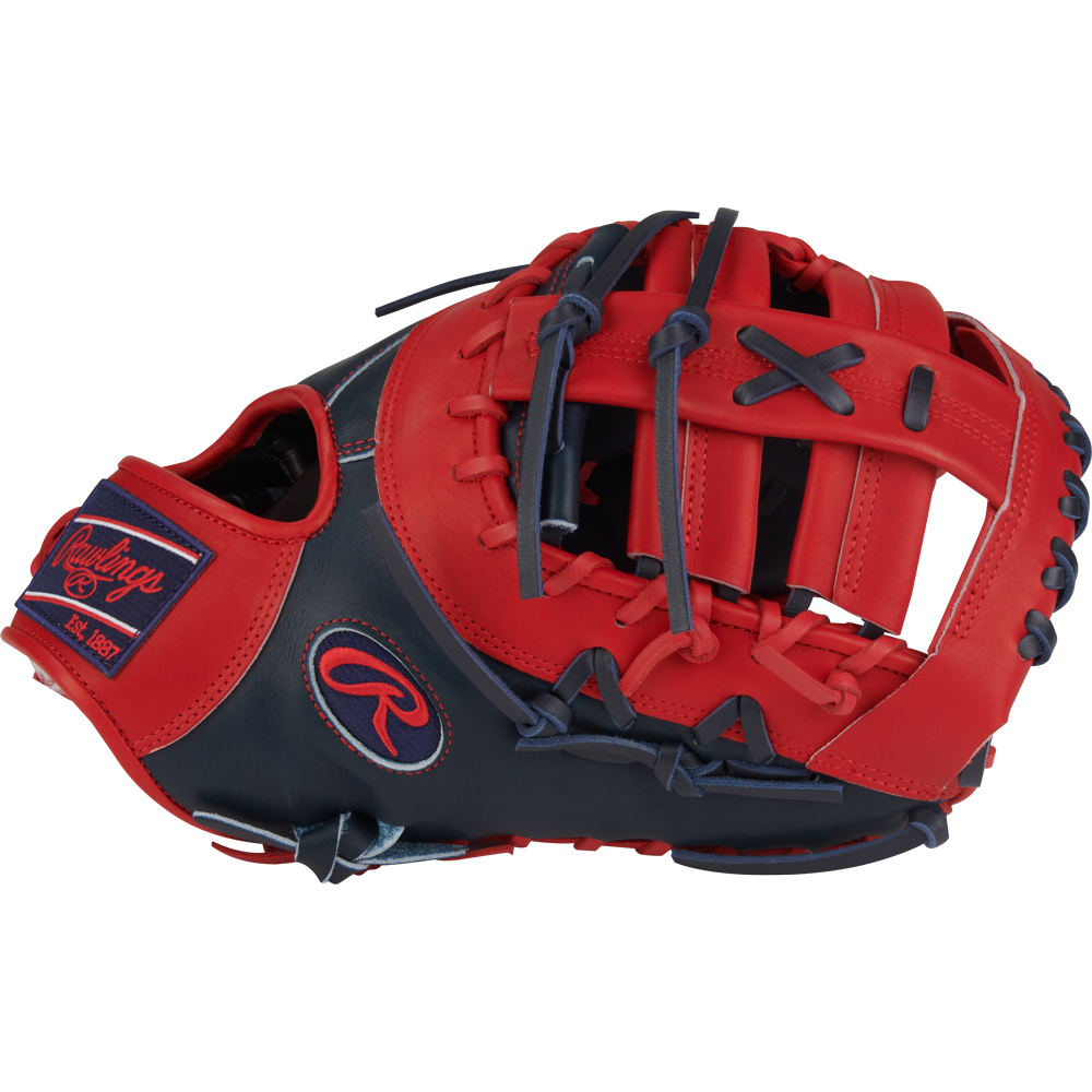 A Rawlings Pro Preferred 13" Vladimir Guerrero JR Gameday First Base Mitt (PROSVG27) in red and navy blue is shown from a side angle, featuring visible stitching, webbing, and the Rawlings logo patch on the wrist strap.