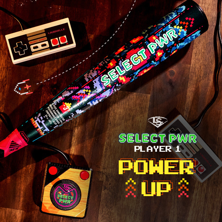 A vibrant 2026 Louisville Slugger Select PWR Player 1 (-3) BBCOR Baseball Bat (WBL4182010) rests on wood among retro game controllers, with "SELECT PWR PLAYER 1 POWER UP" in pixel font—ideal for power hitters.