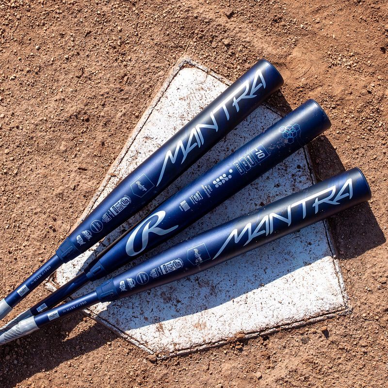 A group of baseball bats, featuring the 2025 Rawlings Mantra (-10) Fastpitch Softball Bat: RFP4M10 (DEMO) by Rawlings, rests on the dirt ground.