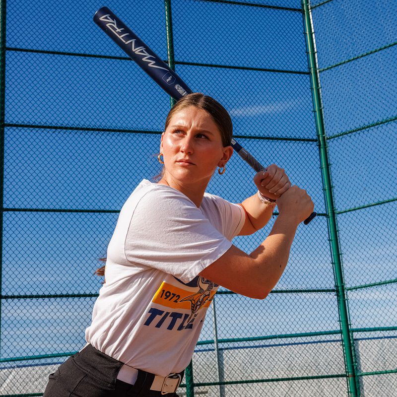 A woman holding a 2025 Rawlings Mantra (-10) Fastpitch Softball Bat: RFP4M10 (DEMO).