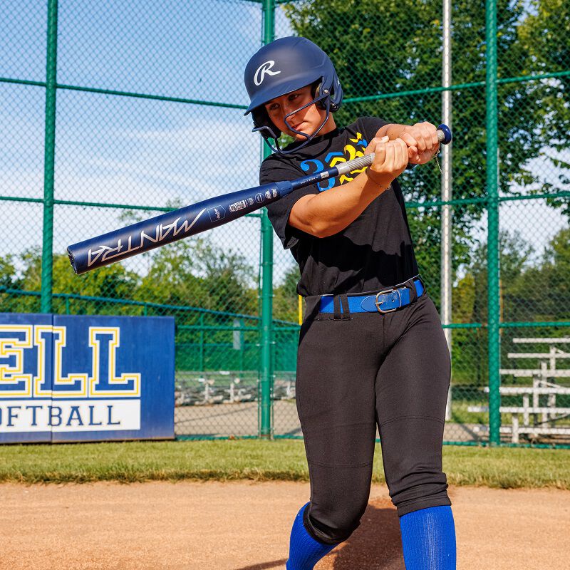A woman holding the 2025 Rawlings Mantra (-9) Fastpitch Softball Bat: RFP4M9 (DEMO) stands ready at the plate.