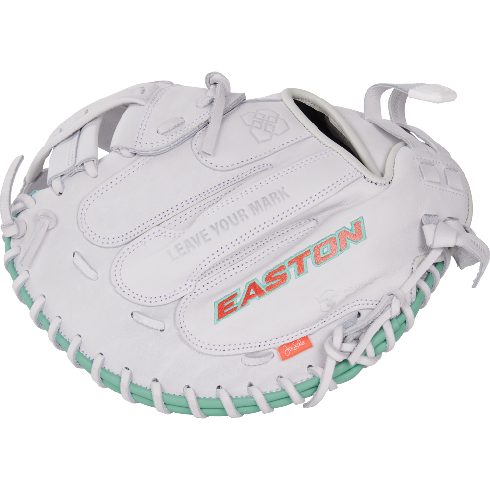 The Easton Jen Schro "The Rudi" 34" Fastpitch Catcher's Mitt (RUDI-2024) features a white design, teal lacing, red-orange EASTON branding, premium USA steerhide leather, and "LEAVE YOUR MARK" embossed above the logo.