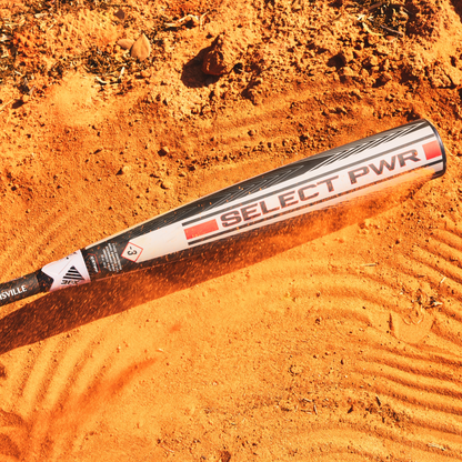 A 2026 Louisville Slugger Select PWR (-3) BBCOR Baseball Bat (WBL4115010) rests on an orange dirt field, its shadow stretching among small rocks—the ideal pick from Louisville Slugger for power hitters seeking elite performance.