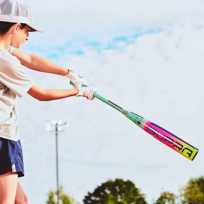 A person in a cap and athletic wear swings the 2027 Louisville Slugger Supra (-5) 2 3/4" USSSA Baseball Bat (WBL4253010) outdoors, with a cloudy sky and trees in the background.
