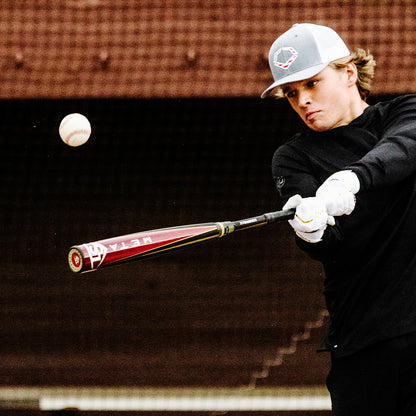 A young baseball player in a cap and black long-sleeve shirt swings a USED 2025 Louisville Slugger Meta (-3) BBCOR Baseball Bat (WBL2966010) during practice.