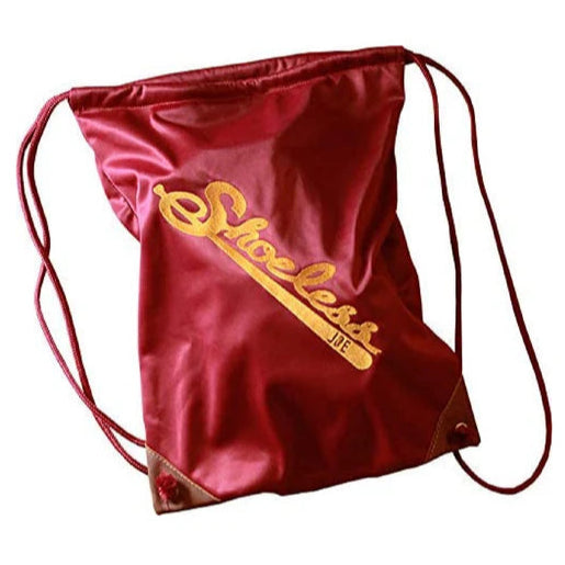 The Shoeless Joe Glove Drawstring Glove Bag is a red, felt-like backpack with yellow "Shoeless Joe" script, brown reinforced corners, and a glove bag design.