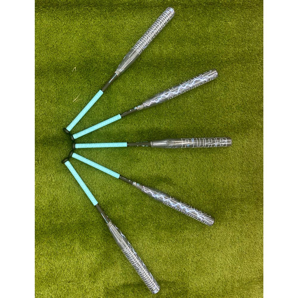 Six Pure Sports Storm Shadow 13″ Balanced USA Slowpitch Softball Bats (5147M91B) with turquoise handles are fanned out on green grass, handles meeting at the center and barrels radiating outward, mirroring the Storm Shadow X22 style.