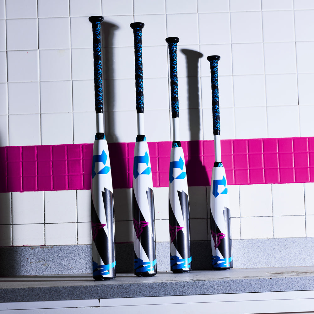 Four baseball bats, including a 2025 DeMarini ZEN (-8) 2 3/4" USSSA Baseball Bat (WBD2533010) by DeMarini, stand upright against a tiled wall with a pink stripe on a gray countertop.
