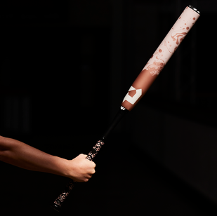 A person’s hand gripping the handle of a maroon and white baseball bat, with the rest of the background dark and out of focus.