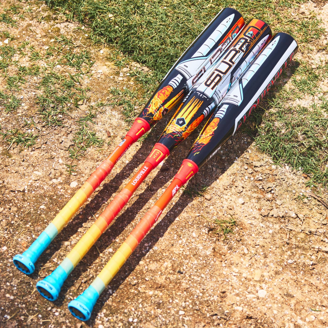 Three colorful Louisville Slugger Supra Starship (-10) 2 3/4" USSSA Baseball Bats (WBL4183010), with vivid orange-to-blue handles and composite barrels, lie parallel on dirt and grass, their eye-catching designs facing up.
