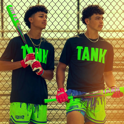 Two young men stand by a chain-link fence, each holding a Soldier Sports 2026 Soldier Tank2 (-3) BBCOR Baseball Bat (BB-1-26). They wear matching black shirts with TANK in bright green and neon green paint-splatter shorts.