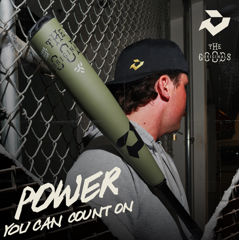A man in a gray hoodie and black cap rests a green baseball bat on his shoulder, standing near a chain-link fence. Bold text reads, POWER YOU CAN COUNT ON, with logos and The Origins branding visible.
