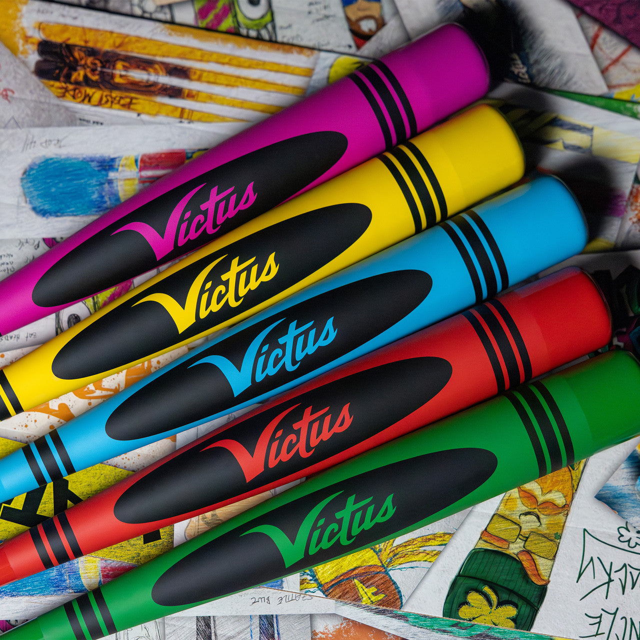 Five colorful Victus 2025 Vibe Crayon (-10) USA Baseball Bats are stacked on comic-style artwork. Each bat features a vibration-reducing knob for comfort and the iconic one-piece aluminum design.