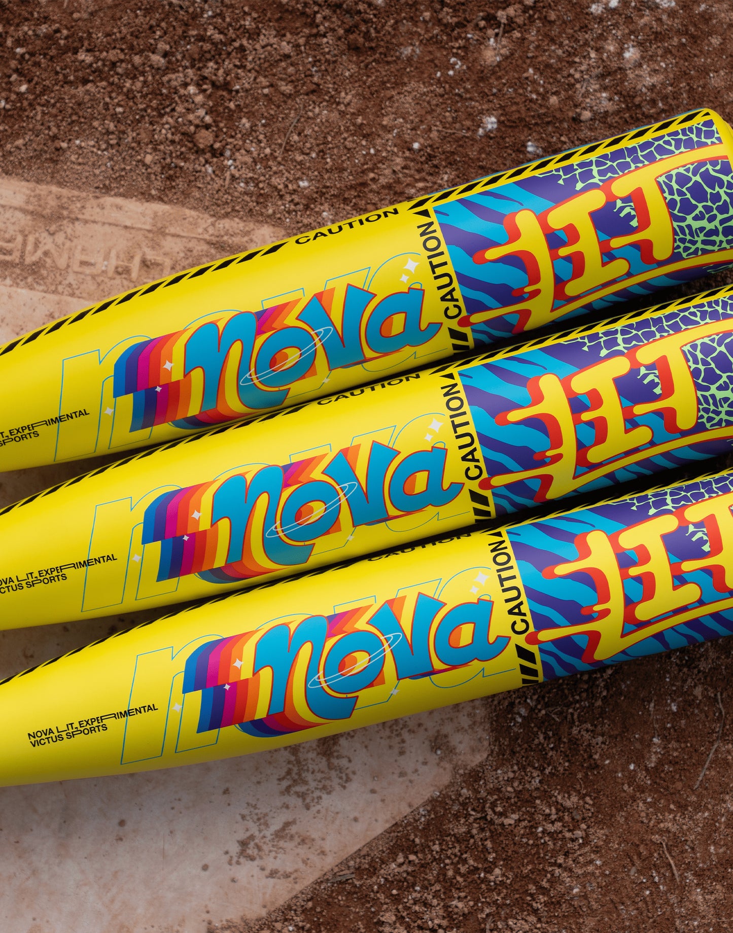 Three vibrant Victus Nova Lit (-10) 2 3/4" USSSA Baseball Bats (VSBNL10) feature bold blue, red, and orange designs with "CAUTION" printed near the barrel tips, displayed side by side on a textured brown surface.