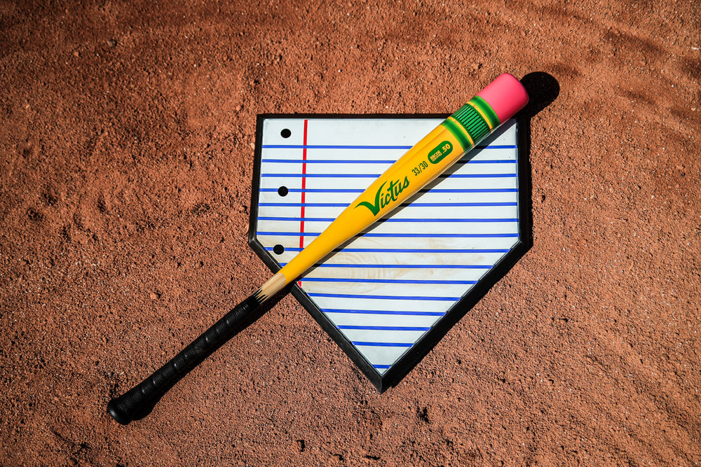 The 2025 Victus Vibe Pencil (-5) 2 3/4" USSSA Baseball Bat by Victus, shown in yellow and black, rests on white and blue paper. It's crafted from high-performance aluminum alloy for superior strength.