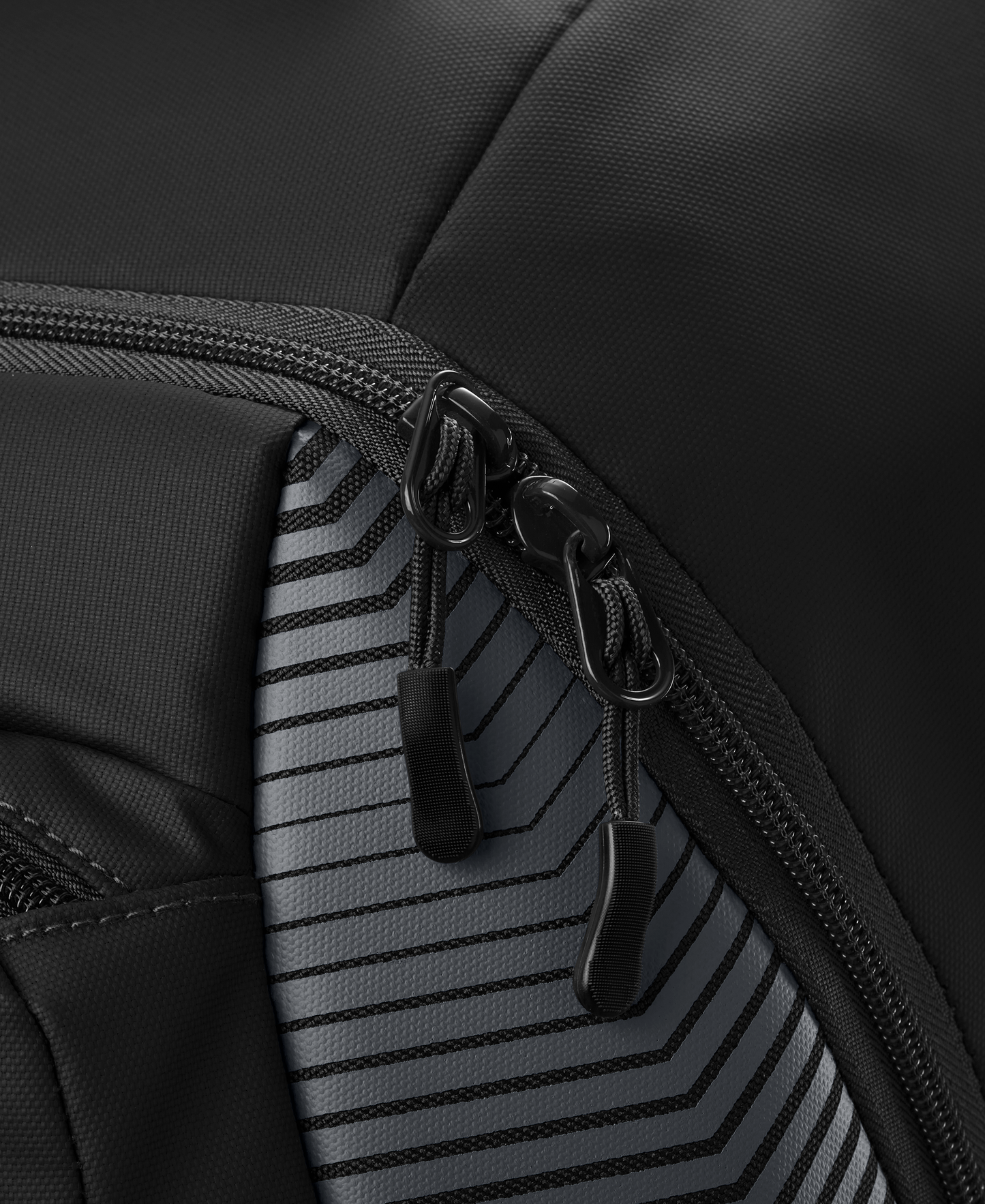 Close-up of two black zipper pulls on the EvoShield Tone Set Backpack (WB57304) by EvoShield, featuring water-resistant, durable fabric with a gray and black geometric striped pattern—perfect as a baseball gear bag.