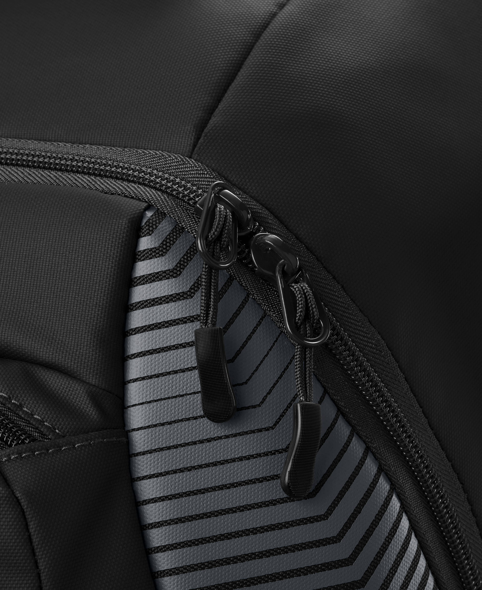 Close-up of two black zipper pulls on the EvoShield Tone Set Backpack (WB57304) by EvoShield, featuring water-resistant, durable fabric with a gray and black geometric striped pattern—perfect as a baseball gear bag.