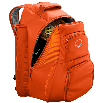 The EvoShield Tone Set Backpack (WB57304) by EvoShield is an orange, water-resistant backpack with multiple zippered compartments, bat sleeves, a top handle, padded straps, and sports gear inside like a yellow and black helmet.