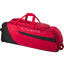 The EvoShield Takeover Wheeled Bag (WB57572) is a spacious red and black gear bag featuring a top handle, side mesh pocket, zippered compartments, and bat sleeves for easy baseball equipment transport.
