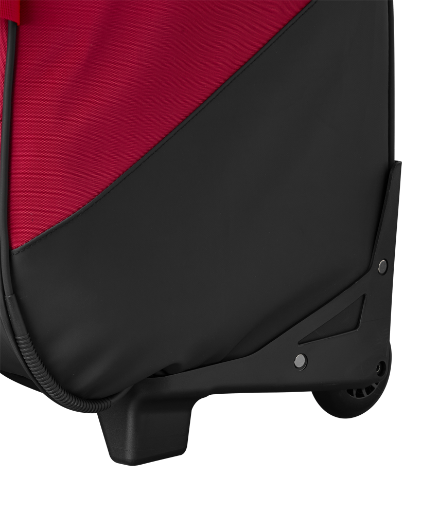 Close-up of the bottom corner of the EvoShield Takeover Wheeled Bag (WB57572) in red and black, showing the wheel, sturdy plastic base, and durable fabric material.