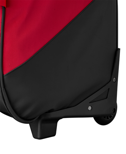 Close-up of the bottom corner of the EvoShield Takeover Wheeled Bag (WB57572) in red and black, showing the wheel, sturdy plastic base, and durable fabric material.
