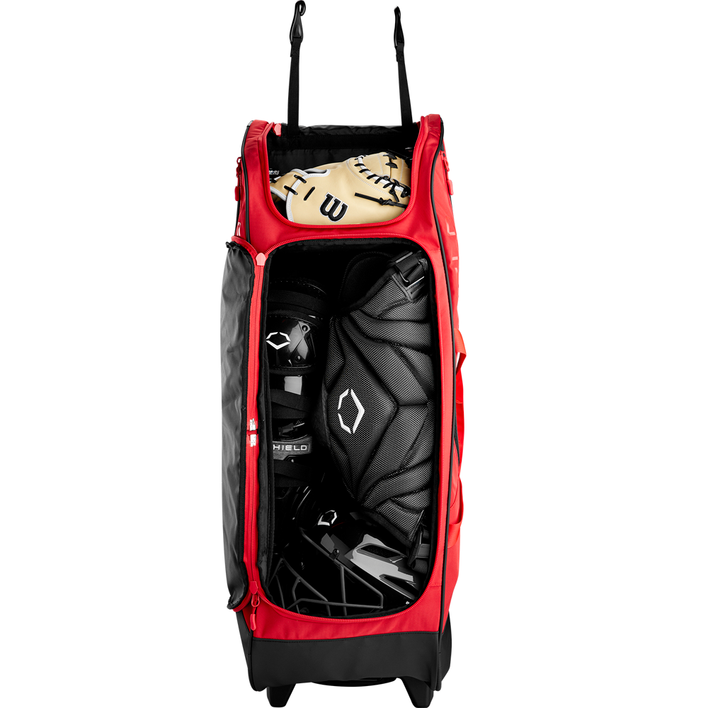 The EvoShield Takeover Wheeled Bag (WB57572) by EvoShield, shown in red and unzipped to reveal black catcher's gear and a tan glove inside, is displayed against a plain white background.
