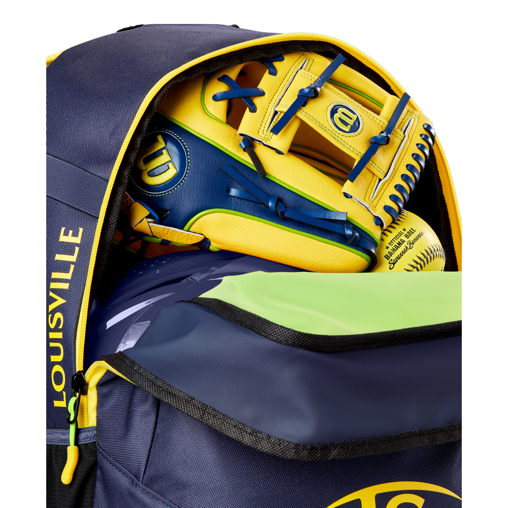 A close-up of a partially unzipped navy and yellow Louisville Slugger Savannah Bananas Powerized Stick Pack Backpack (WB57636) shows a yellow and blue Wilson baseball glove and a yellow softball inside.