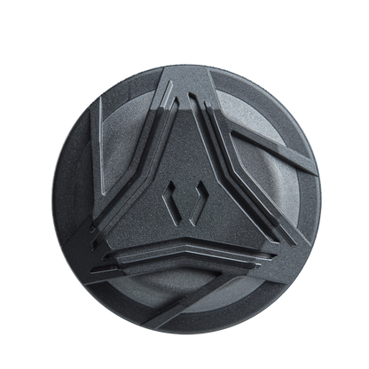 A round, dark gray object with raised angular designs—resembling the detailing of the DeMarini ZEN Limited Edition (-10) USSSA Baseball Bat (WBD2541010) by DeMarini—set against a plain white background.