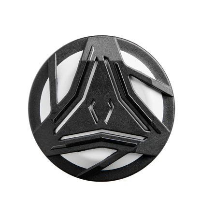 A round, black object featuring geometric cutouts reminiscent of the 2025 DeMarini Whisper (-9) Fastpitch Softball Bat (WBD2545010), its design echoing the bat's futuristic Amplified Gapped Wall Barrel pattern for a strikingly modern look.