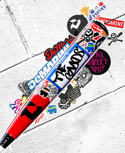 The 2026 DeMarini The Goods Sticker Bomb (-3) BBCOR Baseball Bat (WBD2653010) features bold, vibrant sticker graphics on a white textured background—a striking update to DeMarini's classic BBCOR bat design.