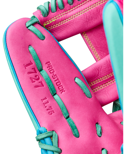 Close-up of a pink Wilson A2000 1727SS 11.5″ Baseball Glove (WBG0009501RT1175) with teal laces. The glove is crafted with SuperSnakeSkin for added durability and has “PRO-STOCK”, “1727”, and “11.75” stamped in red text on the inner palm. Yellow stitching is visible on the wrist area.