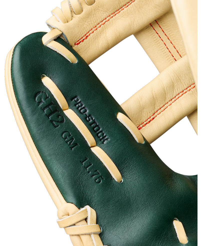 Close-up of a Wilson A2000 GH2 11.75″ Gunnar Henderson GM Baseball Glove (WBG0009601RT1175) featuring green and tan leather, red stitching, and embossed text reading PRO STOCK, 6H2 CM 11.75.