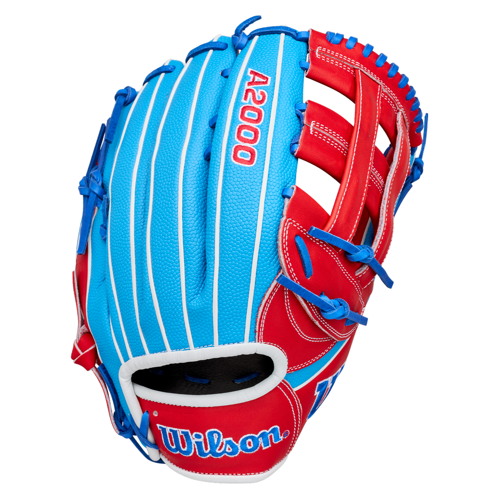 A Wilson A2000 PCA4 12.5″ Pete Crow-Armstrong GM Baseball Glove (WBG0009701) is displayed on a plain white background, featuring a blue and red design with white pinstripes, blue lacing, and the Wilson logo on the wrist strap. This glove is inspired by Pete Crow-Armstrong’s signature model.