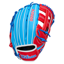 A Wilson A2000 PCA4 12.5″ Pete Crow-Armstrong GM Baseball Glove (WBG0009701) is displayed on a plain white background, featuring a blue and red design with white pinstripes, blue lacing, and the Wilson logo on the wrist strap. This glove is inspired by Pete Crow-Armstrong’s signature model.