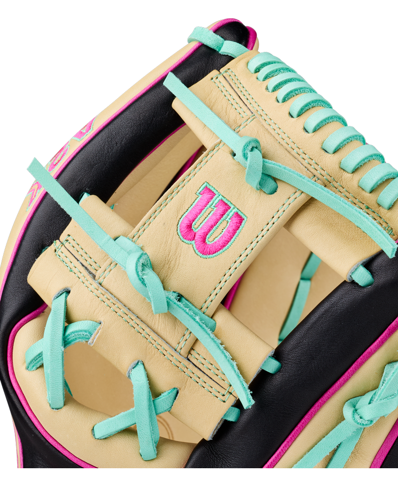 Close-up of the Wilson A2K 1724 11.75″ Baseball Glove (WBG0010201RT1175) by Wilson, showcasing its cream, black, teal, and pink accents—including teal laces and a pink W logo on premium cream leather. Engineered as an infielder’s glove with Double Palm Construction to enhance durability and maintain its shape.