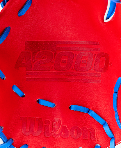 Close-up of the Wilson A2000 1786SS 11.5" Baseball Glove (GOTM July 2026) in red with blue laces, made from Pro Stock leather, featuring an American flag and A2000 embossed above the Wilson logo.