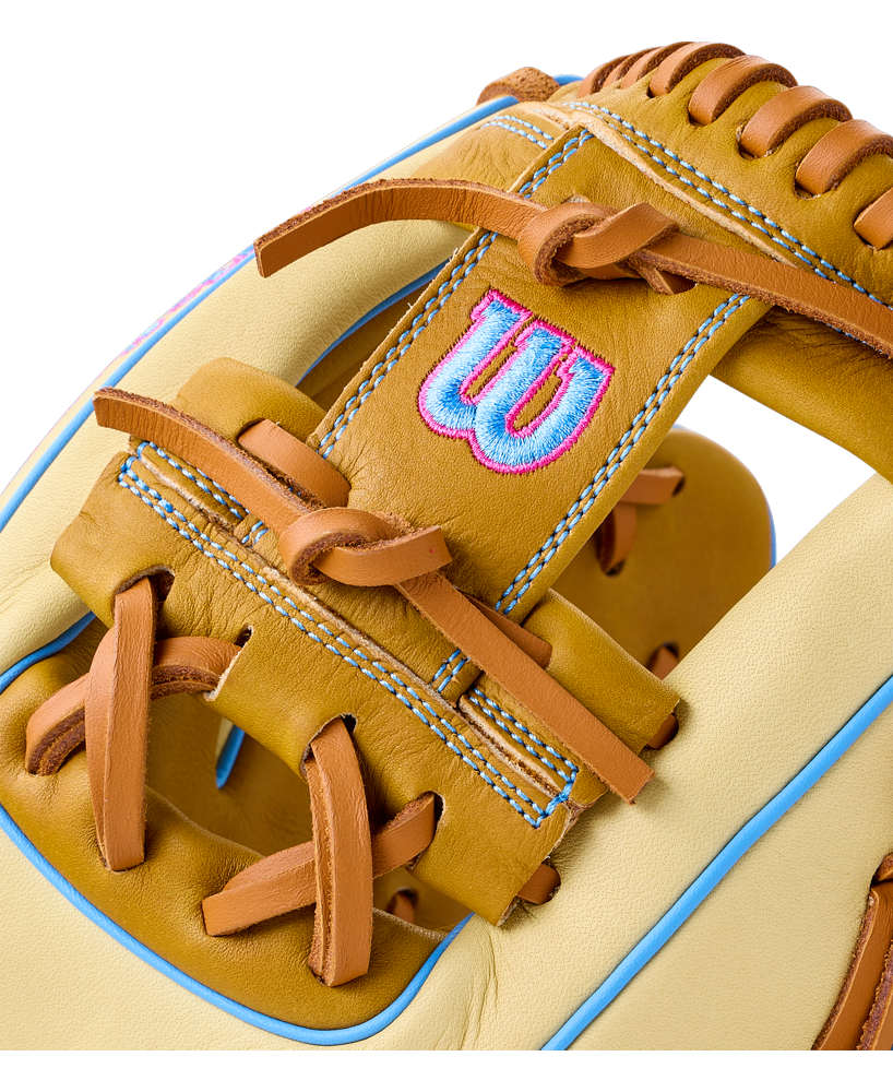 Close-up of a Wilson A1000 1786 11.5″ Baseball Glove: WBG02501RT1786 in tan and cream with light blue accents and an embroidered blue and pink logo on the wrist strap.