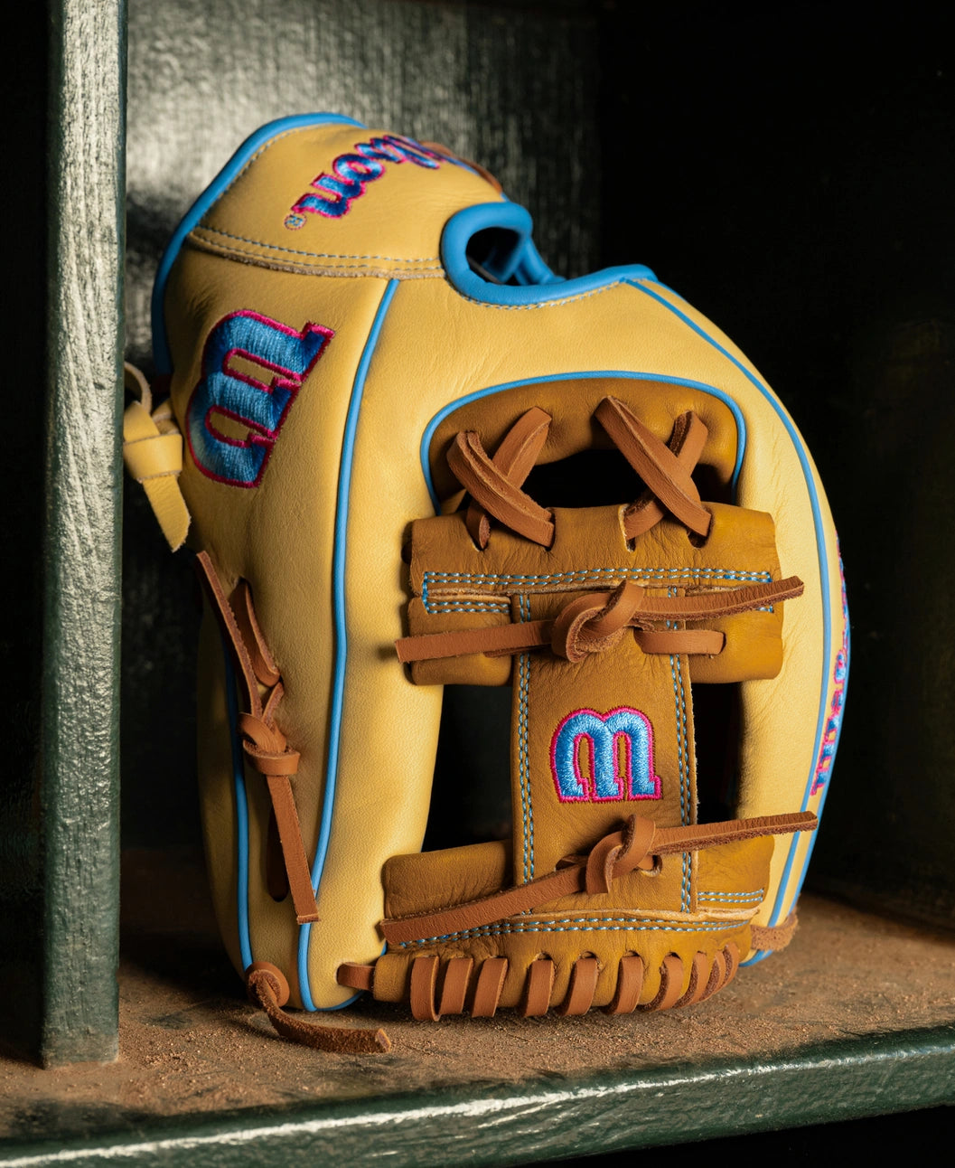 Wilson A1000 1786 11.5″ Baseball Glove: WBG02501RT1786 with tan leather, blue piping, brown leather webbing, and pink and blue embroidered logos.