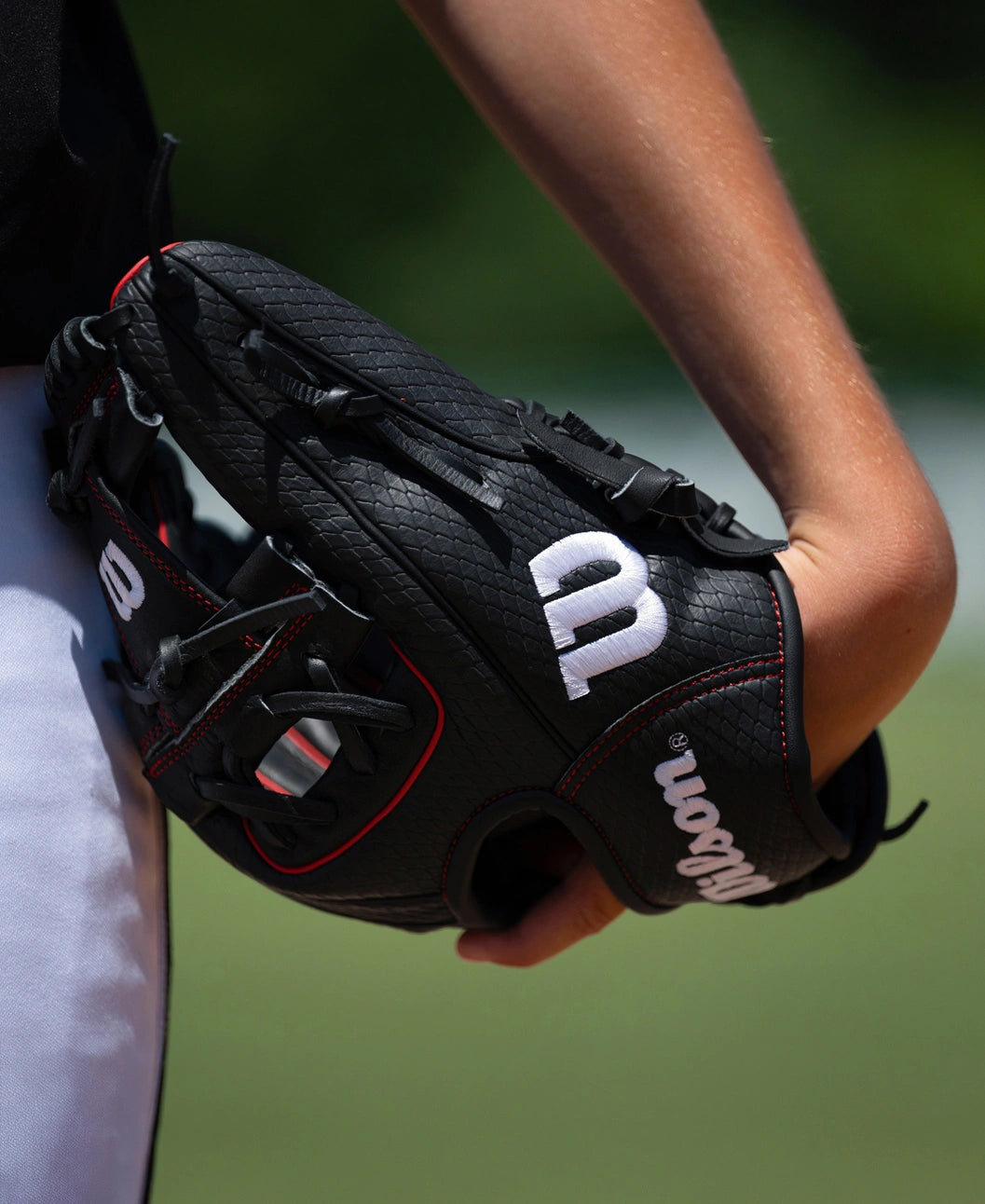 A person holding a black Wilson A1000 1975SS 11.75″ Baseball Glove with red piping and white logos.