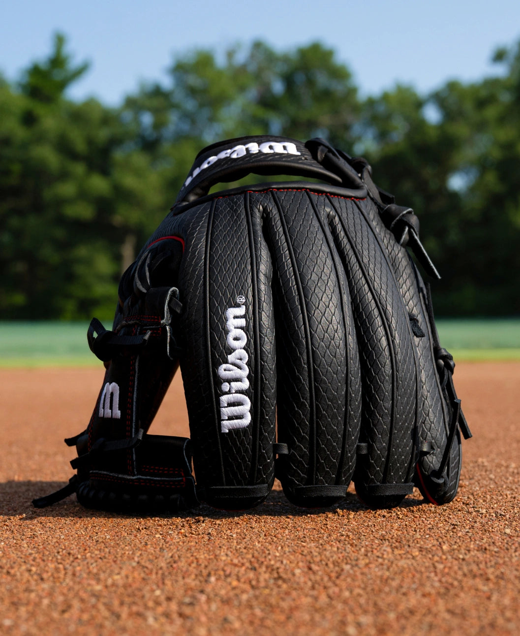 Wilson A1000 1975SS 11.75″ Baseball Glove made of full grain leather with a textured pattern sitting on a dirt infield.
