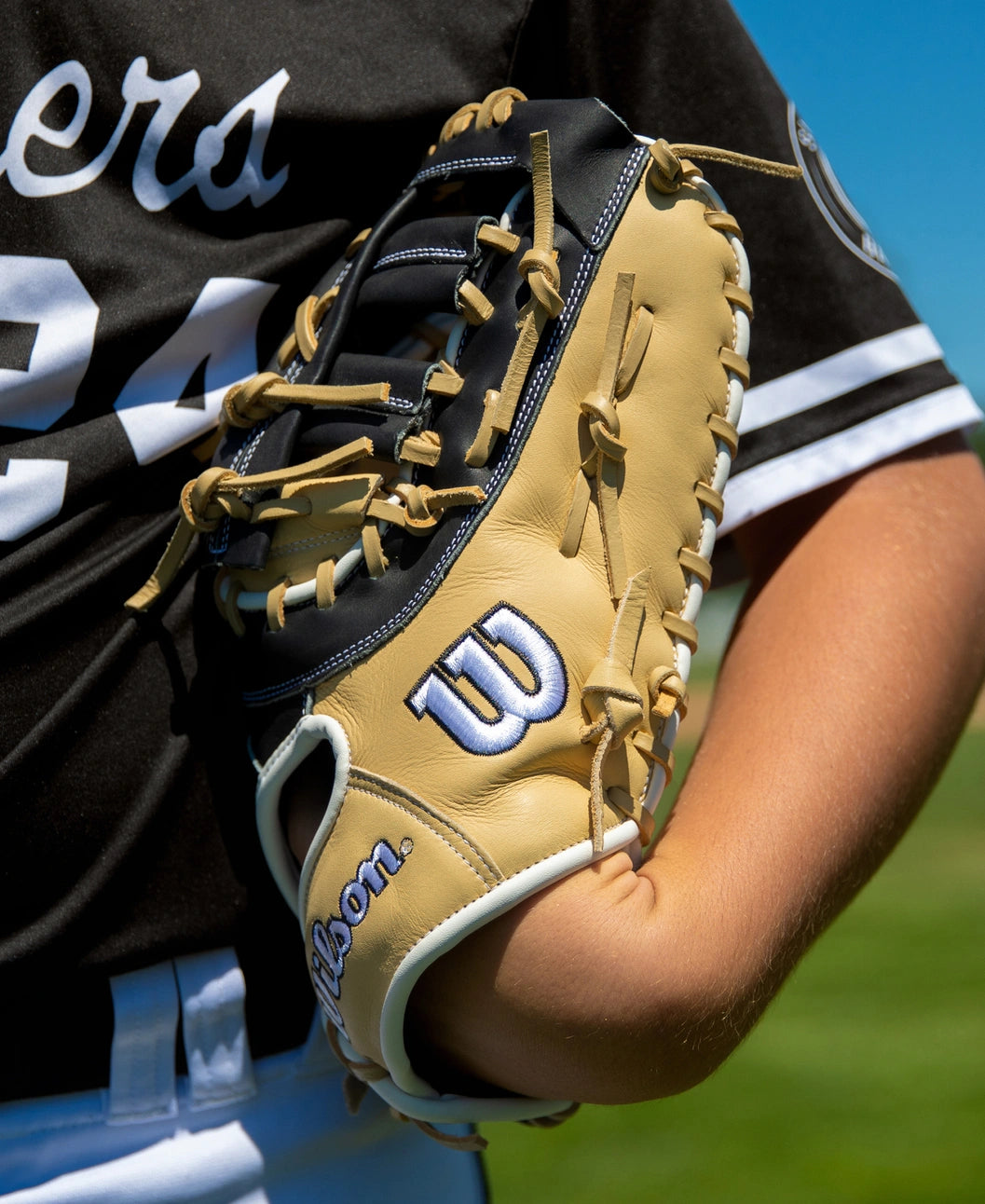 A tan and black Wilson A1000 PF1612 12″ Baseball First Base Mitt held against a player’s side.