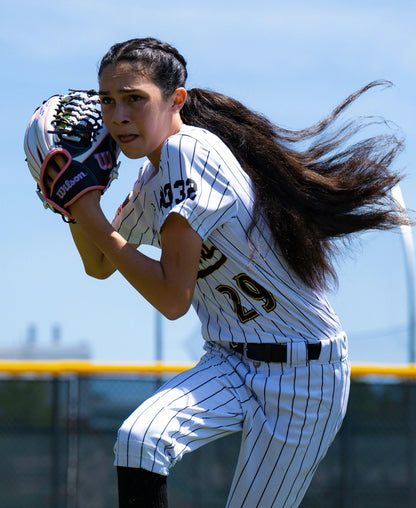 A softball player in a pinstriped uniform prepares to catch a ball with her Wilson A1000 T125 12.5″ Fastpitch Glove.