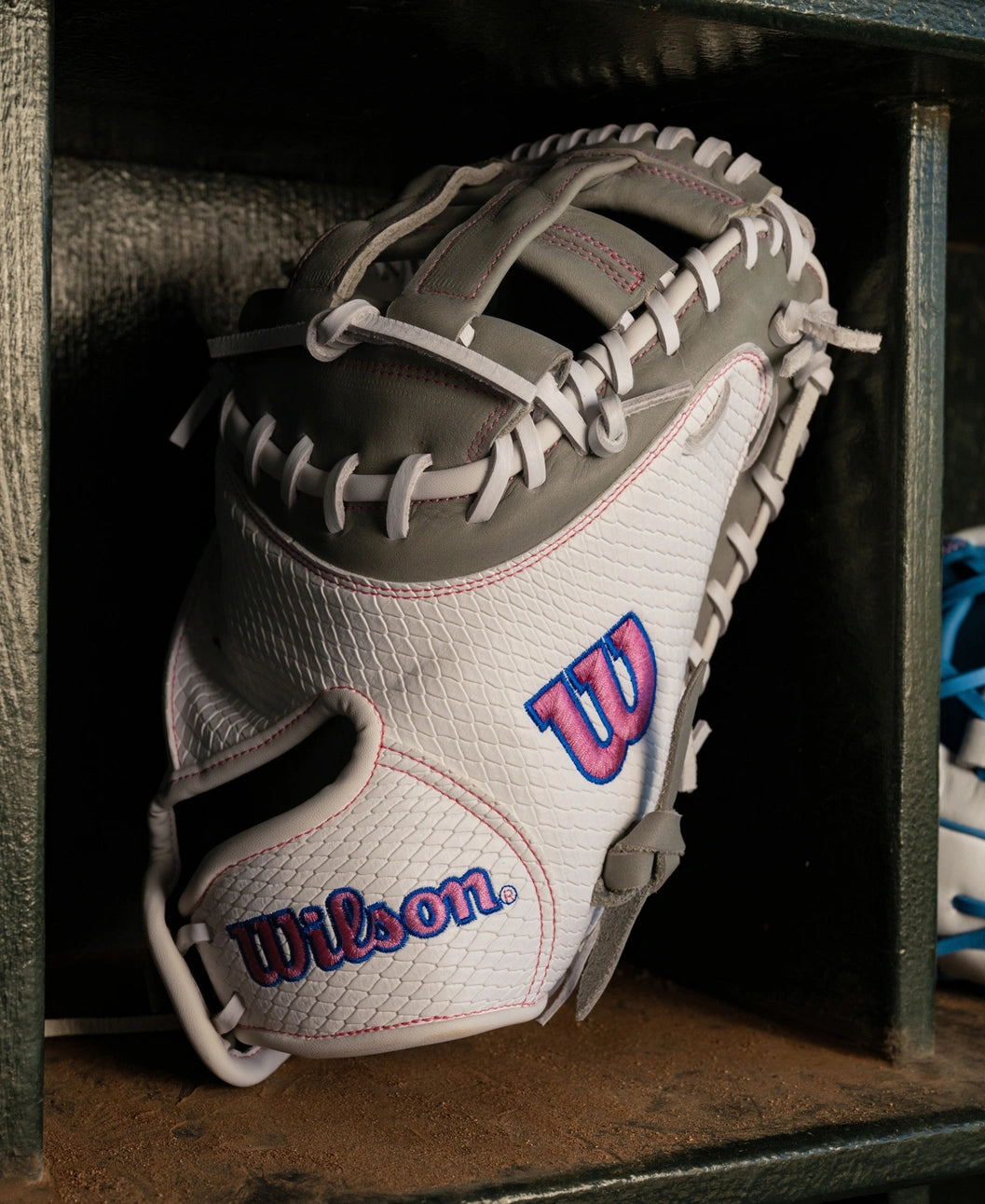 White and grey Wilson A1000 FPCM33 33″ Fastpitch Catcher’s Mitt: WBG03801RTFC33 with pink and blue logos.