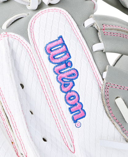 Close-up of a white and gray Wilson A1000 FPCM33 33″ Fastpitch Catcher’s Mitt with pink stitching and the brand name embroidered in blue and pink.