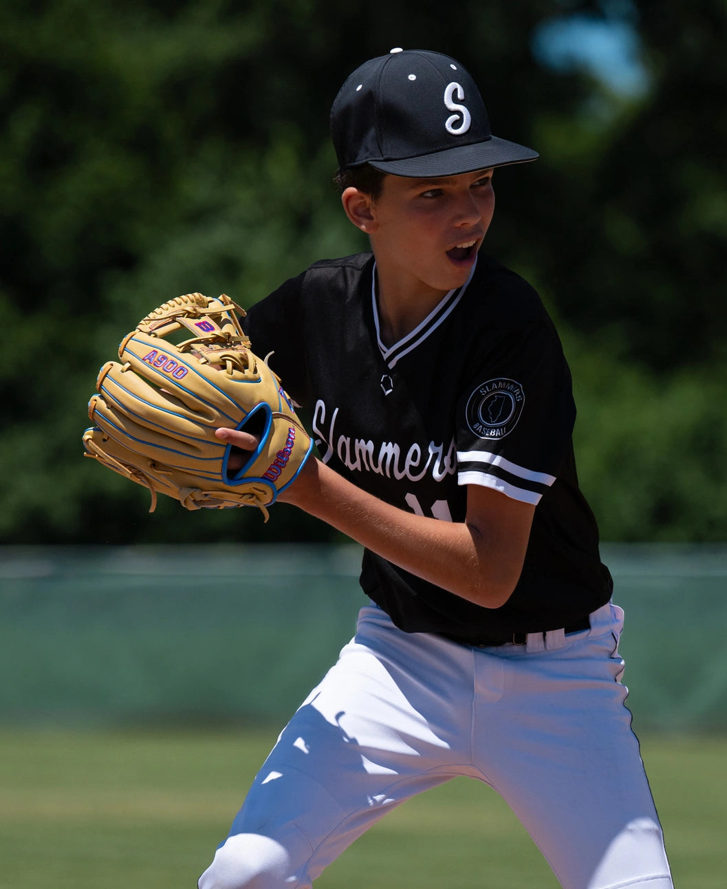 A baseball player in a black and white uniform holding a tan leather Wilson A900 11.5″ Baseball Glove: WBG04002RT115.