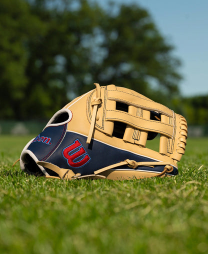 A tan and navy blue Wilson A900 12″ Baseball Glove: WBG04101RT12 resting on a grassy field.
